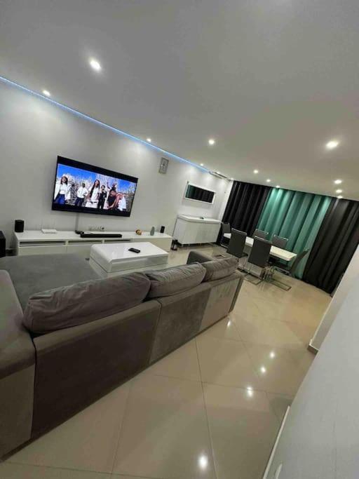 ein Wohnzimmer mit einem Sofa und einem Flachbild-TV in der Unterkunft Appartement cosy et spacieux in Praia