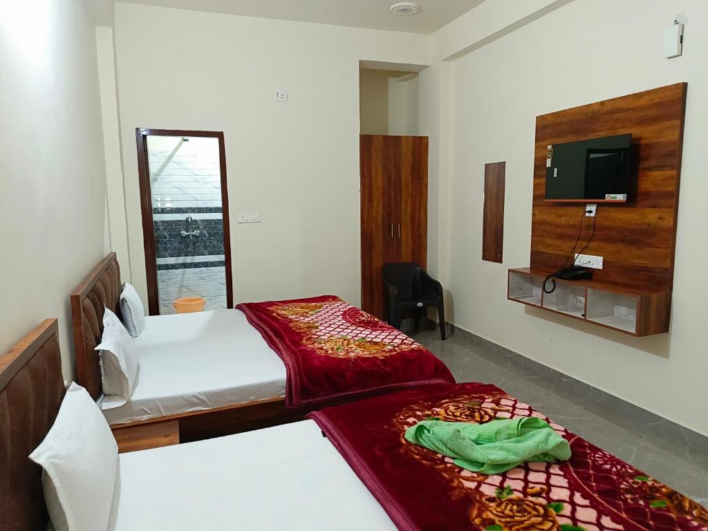 a bedroom with two beds and a tv on the wall at Shri Girraj Residency in Mathura