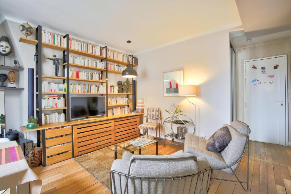 - un salon avec une télévision et des étagères dans l'établissement L'Elégance à la Butte aux Cailles, à Paris