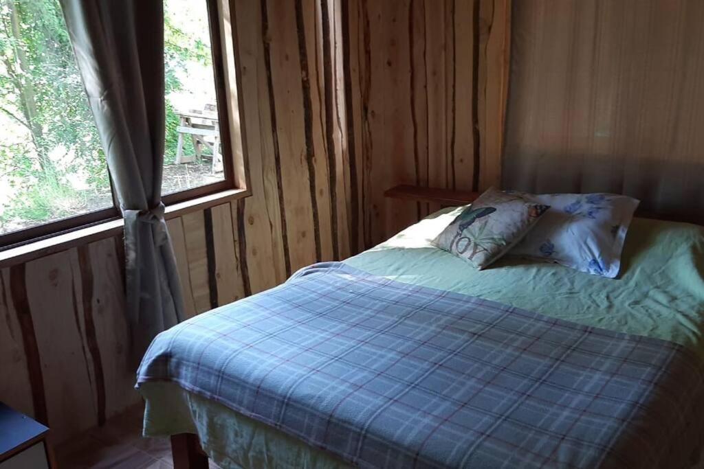 1 dormitorio con 1 cama con edredón azul y ventana en Casa tranquila amueblada, en Pichare