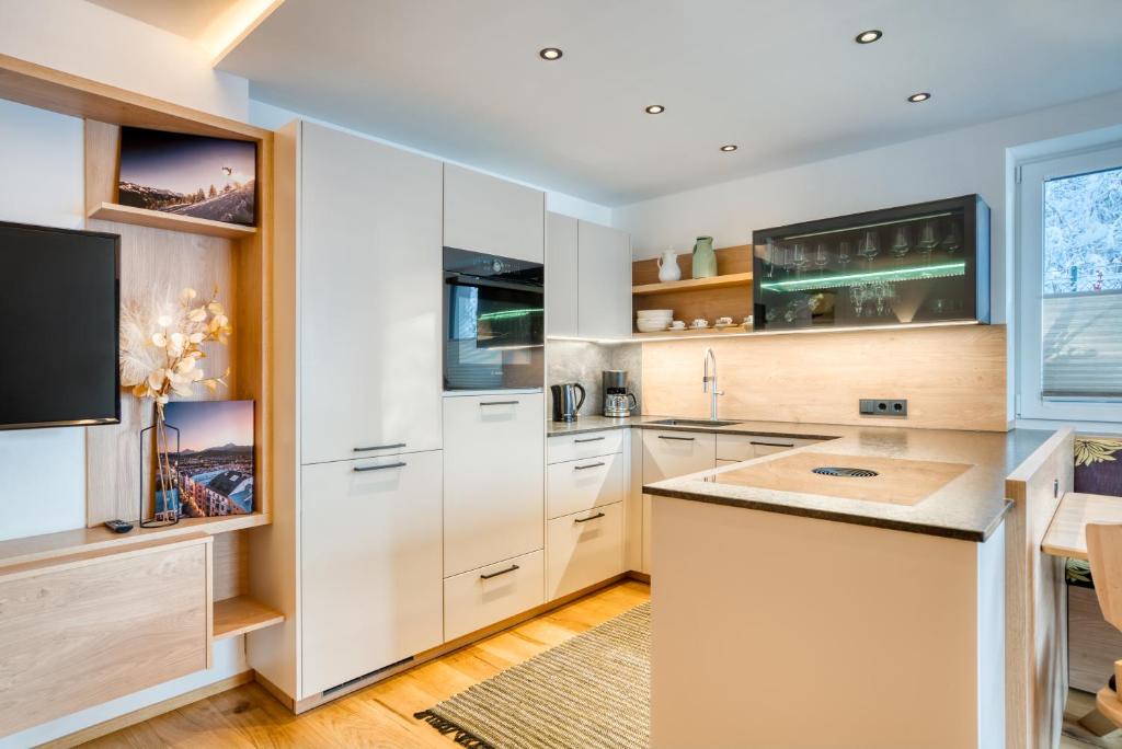 因斯布魯克的住宿－INN Sun Apartment，厨房配有白色橱柜和平面电视。