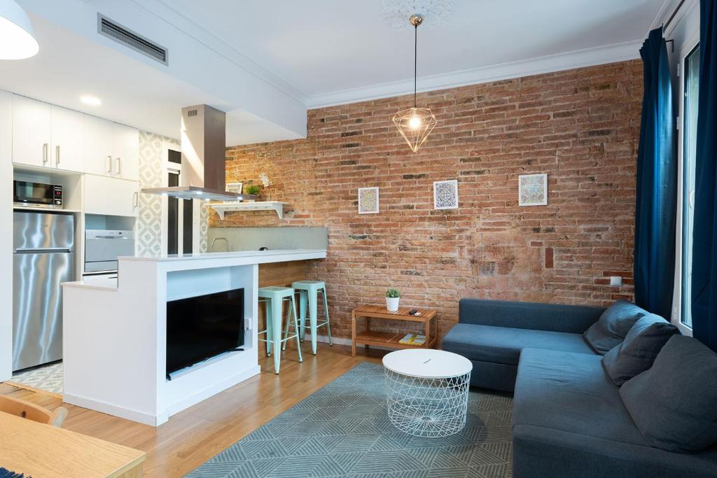 een woonkamer met een blauwe bank en een bakstenen muur bij Bright and cozy flat in the heart of the city in Barcelona