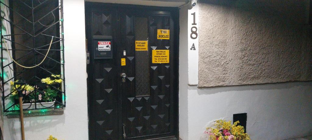 a black door with signs on it next to a building at Uslugi Hotelowe Władysław in Paczków