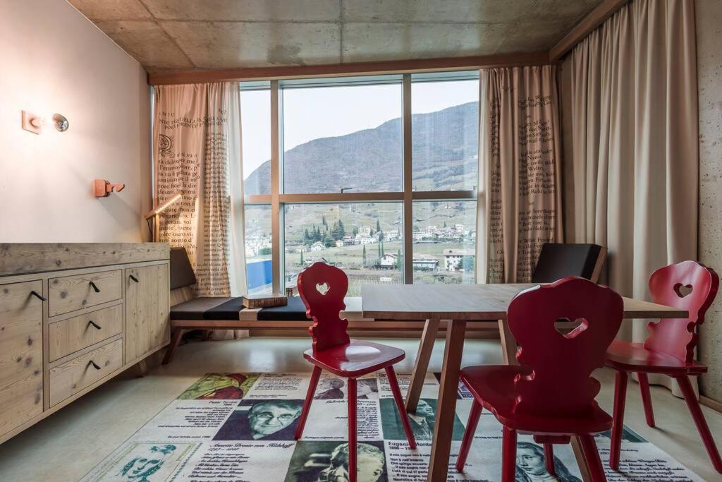una sala da pranzo con tavolo e sedie e una grande finestra di Dichterstube im Living Kampill a Bolzano