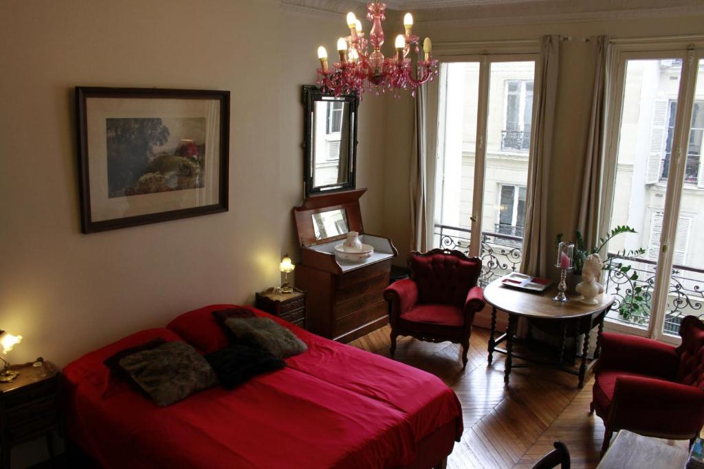 1 dormitorio con cama roja y lámpara de araña en A Room In Paris, en París