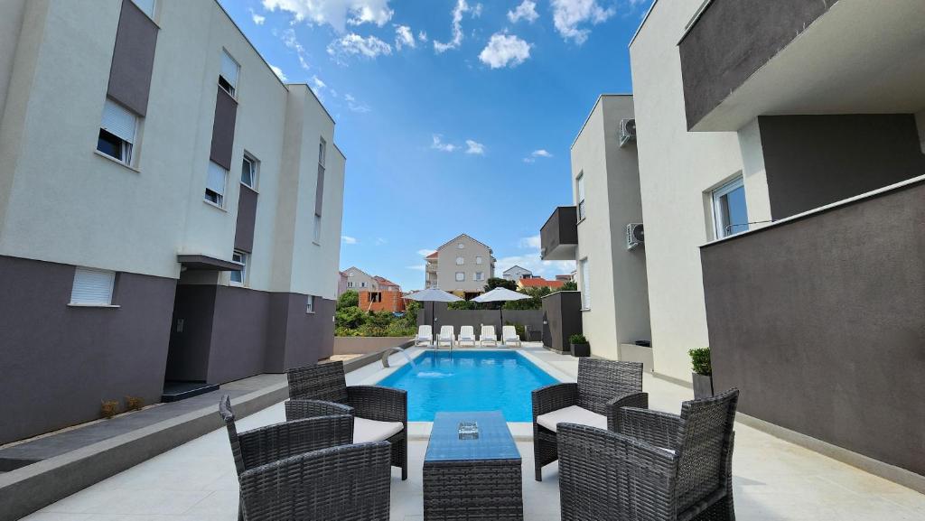 un patio con sillas y una piscina en un edificio en The Sands LUXE Pool Aparthotel 3, en Novalja