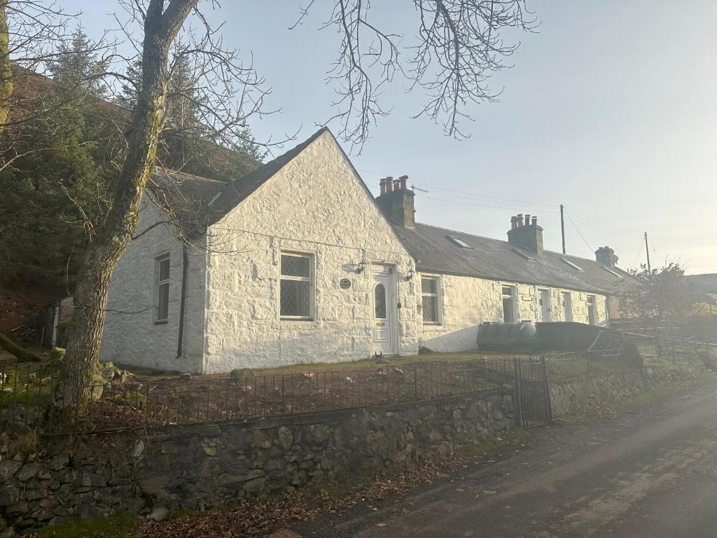 3 Bed Cottage in the Peaceful Village Wanlockhead في Wanlockhead: بيت حجري ابيض بجدار حجري بجانب شارع