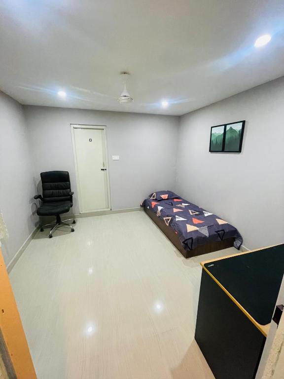 Habitación con cama y silla. en vaishnav cottage en Agartala