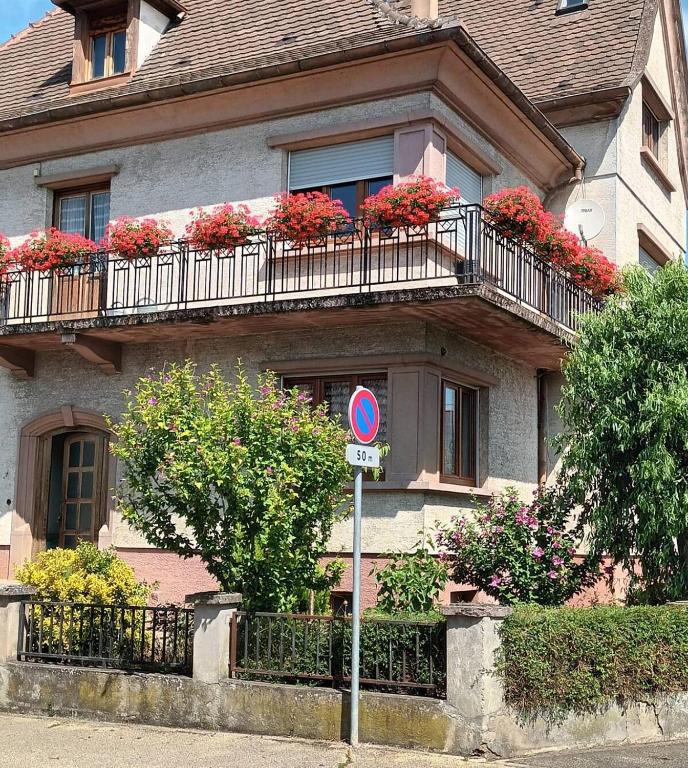 une maison avec des fleurs sur les balcons et un panneau de rue dans l'établissement Appartement pour 7 pers au coeur de l'Alsace, à Muttersholtz