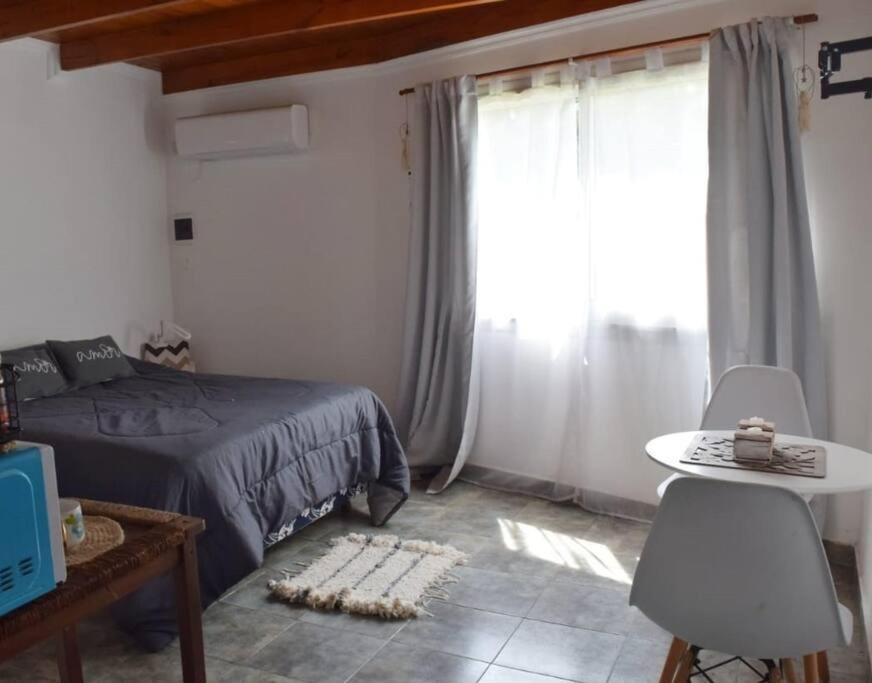1 dormitorio con cama, mesa y ventana en Nómade Habitación en Rufino