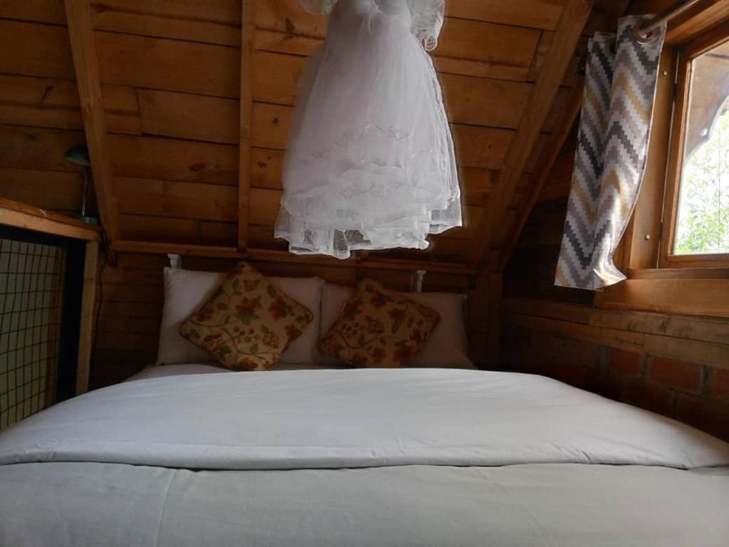 un vestido de novia colgando sobre una cama en una cabaña en The Rustic Gorilla Cabin-Bwindi, en Kinkizi
