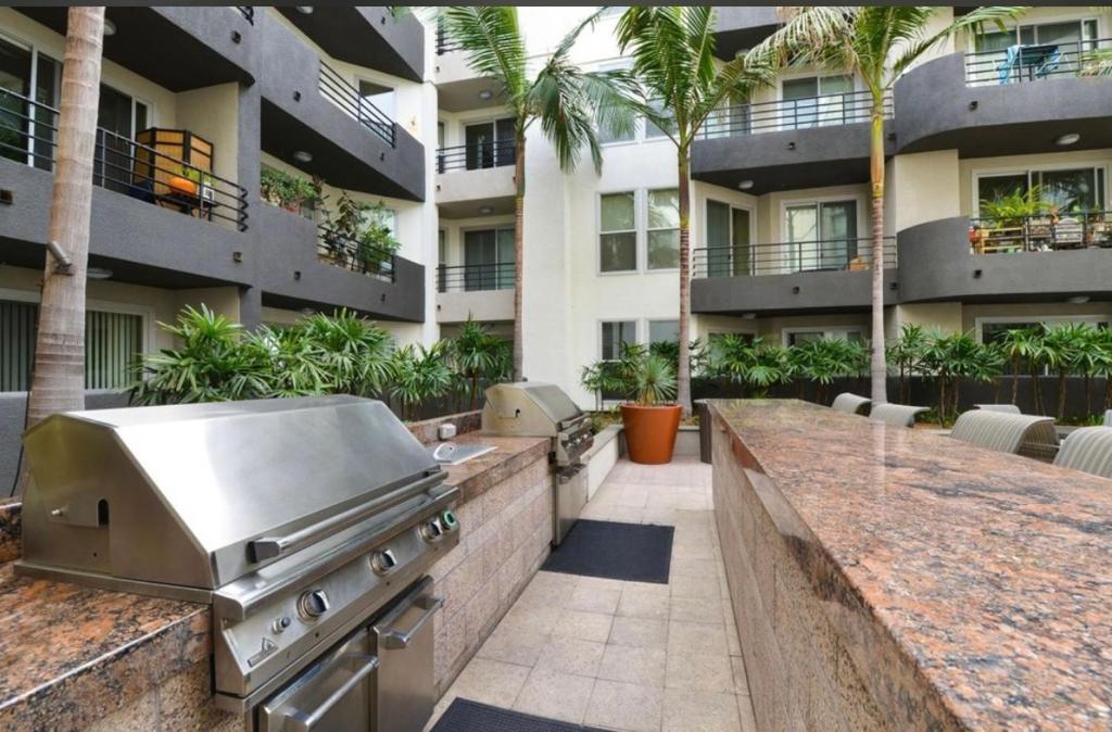 an outdoor kitchen with a grill and a building at Spacious and Central with a Pool View in Los Angeles