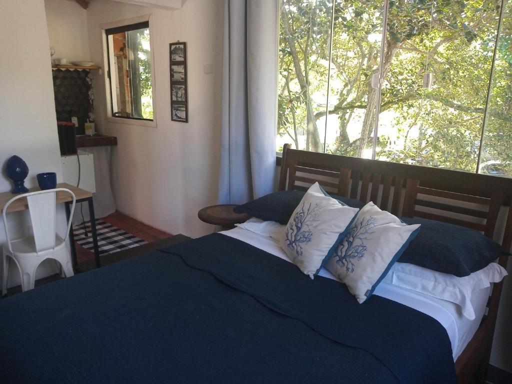 a bedroom with a bed with pillows and a window at Caza di Zaia - kitnet in Búzios