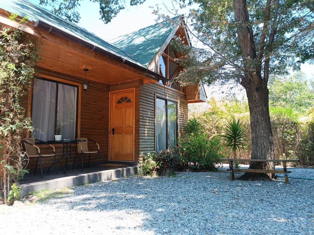 una casa de madera con una mesa y un árbol en Cabaña El Tiempo Es Arte, en San José de Maipo