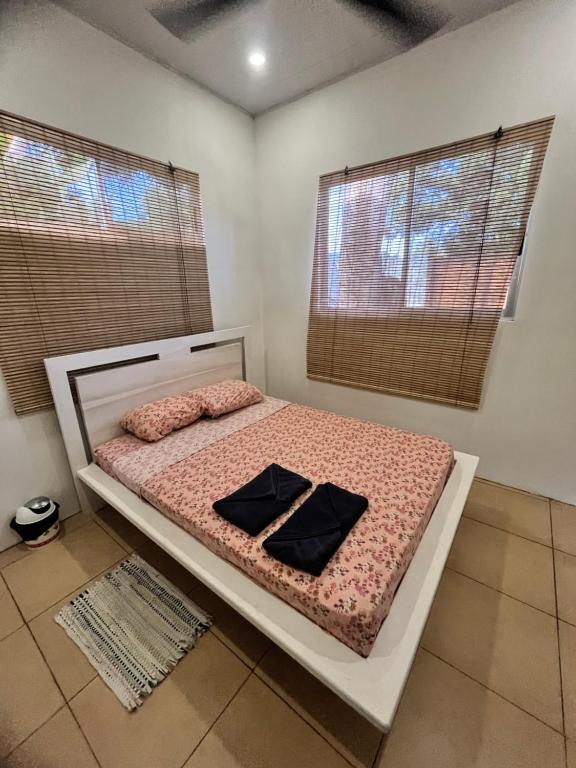 a bed in a room with two windows and a bedvisor at Casita Miss Sam en el Centro de Puerto Viejo in Puerto Viejo