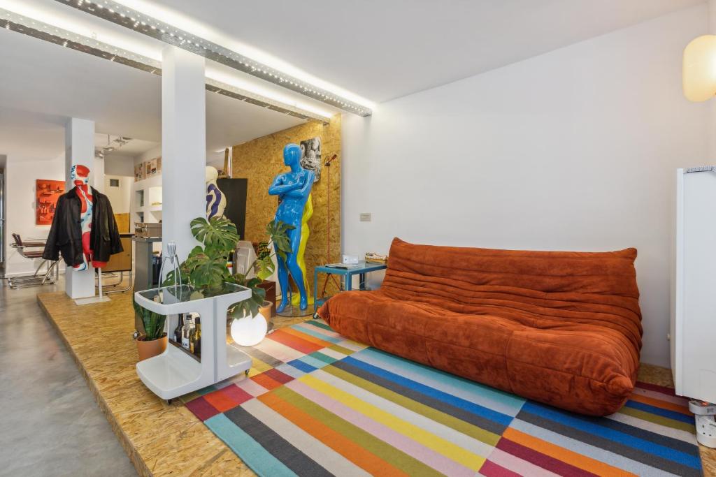 een woonkamer met een oranje bank en een kleurrijk tapijt bij Cosy art studio near station with bikes and garden in Gent