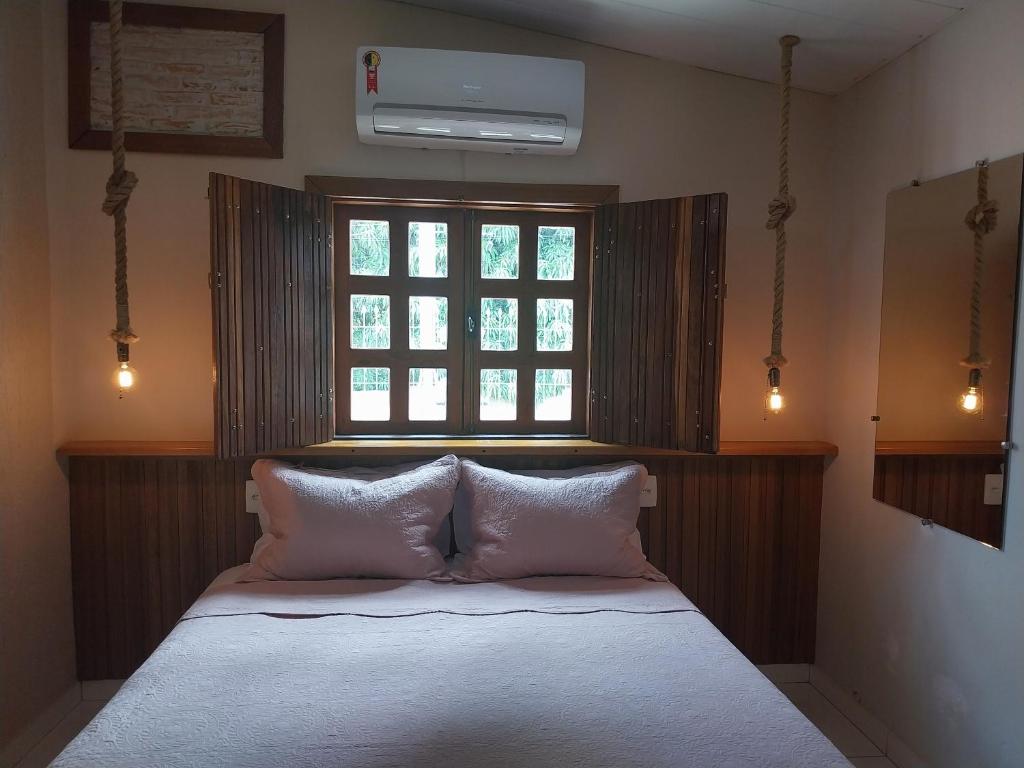 Schlafzimmer mit einem Bett mit weißer Bettwäsche und einem Fenster in der Unterkunft Suítes Pirenópolis Piri in Pirenópolis