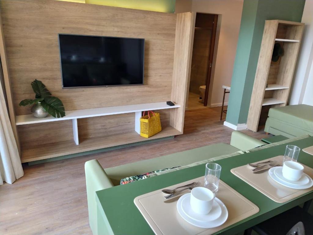 un salon avec une table et une télévision dans l'établissement Hot Beach Suites - Apartamento, à Olímpia