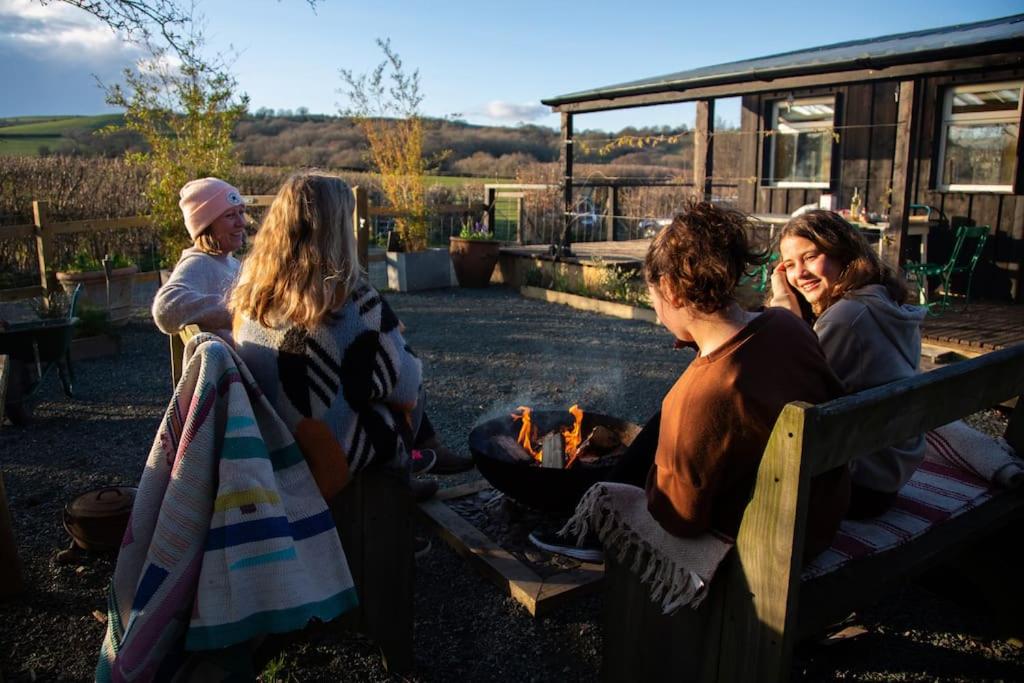 een groep vrouwen die rond een vuur op een bank zitten bij The Deckhouse, cabin with big deck nr Hay-on-Wye in Rhos-gôch