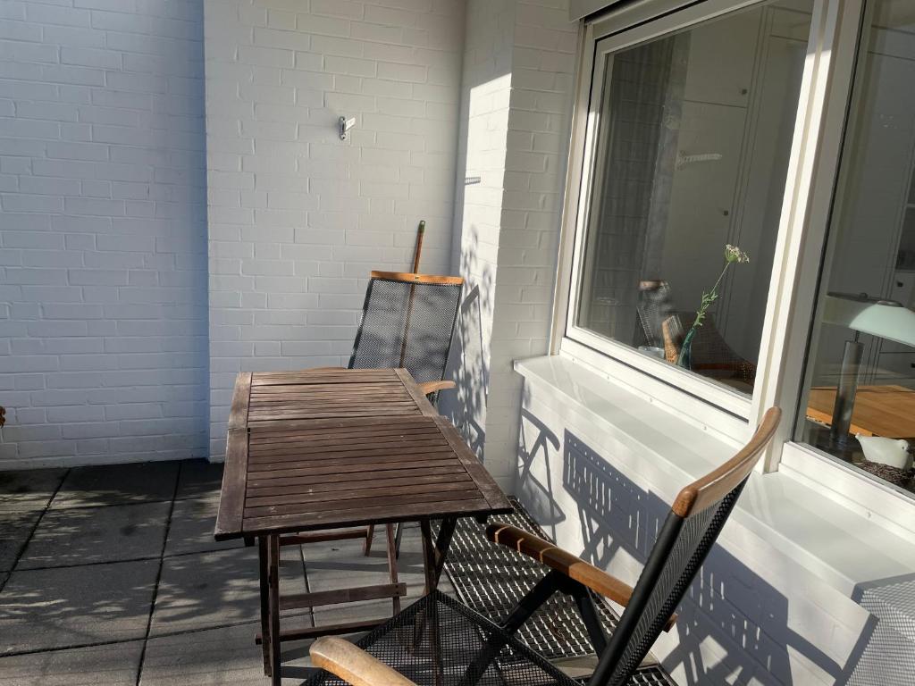 a table and chair on a porch with a dog looking out the window at Dünenrose 21 in Norderney