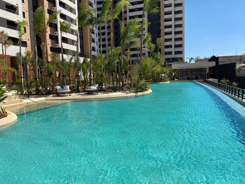 a large swimming pool with palm trees and buildings at Apto Resort Brás Piscina, Ar-condicionado in São Paulo