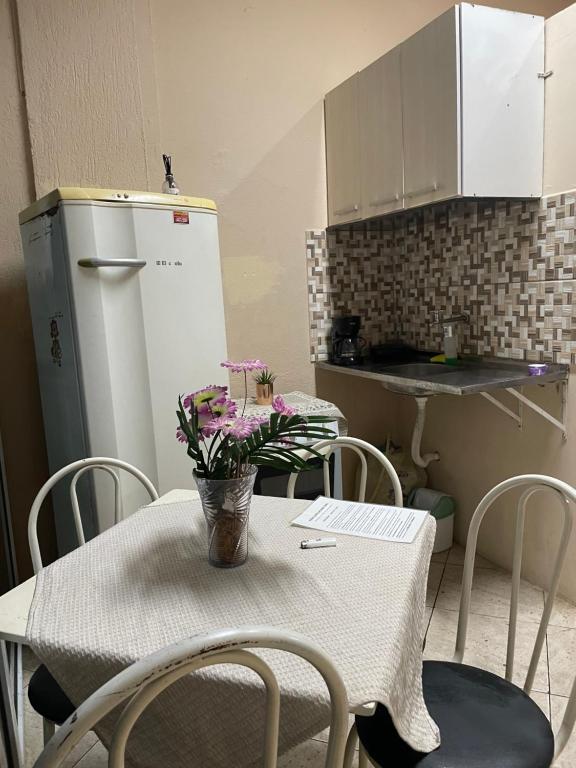 a kitchen with a table with chairs and a refrigerator at Kit Centro Extra in Campos dos Goytacazes