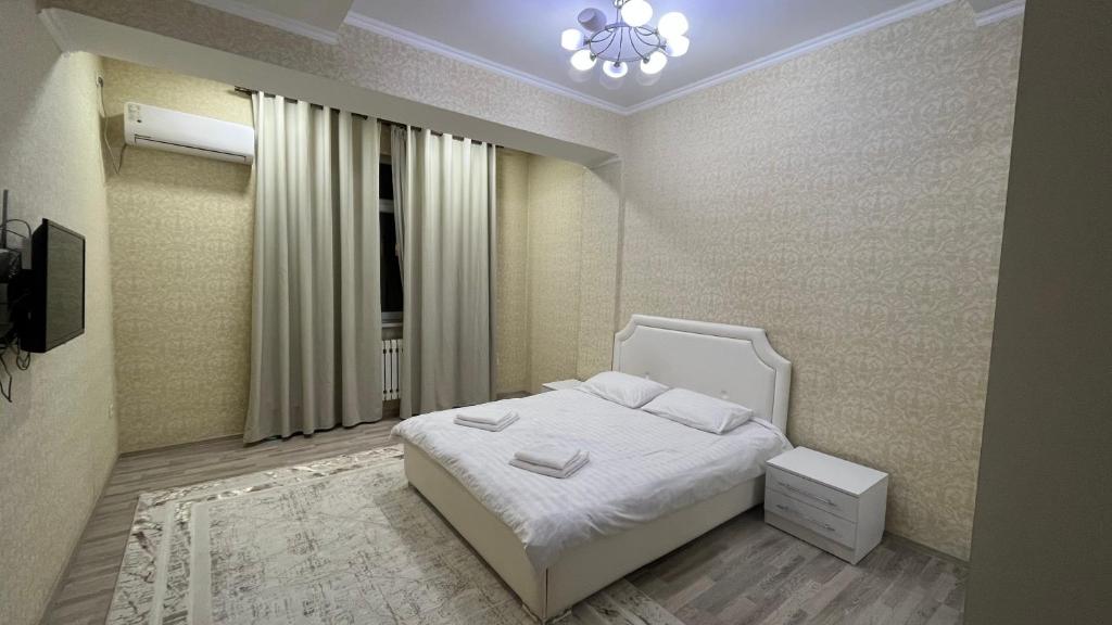 um quarto com uma cama branca e uma janela em Апартамент NUR em Bishkek
