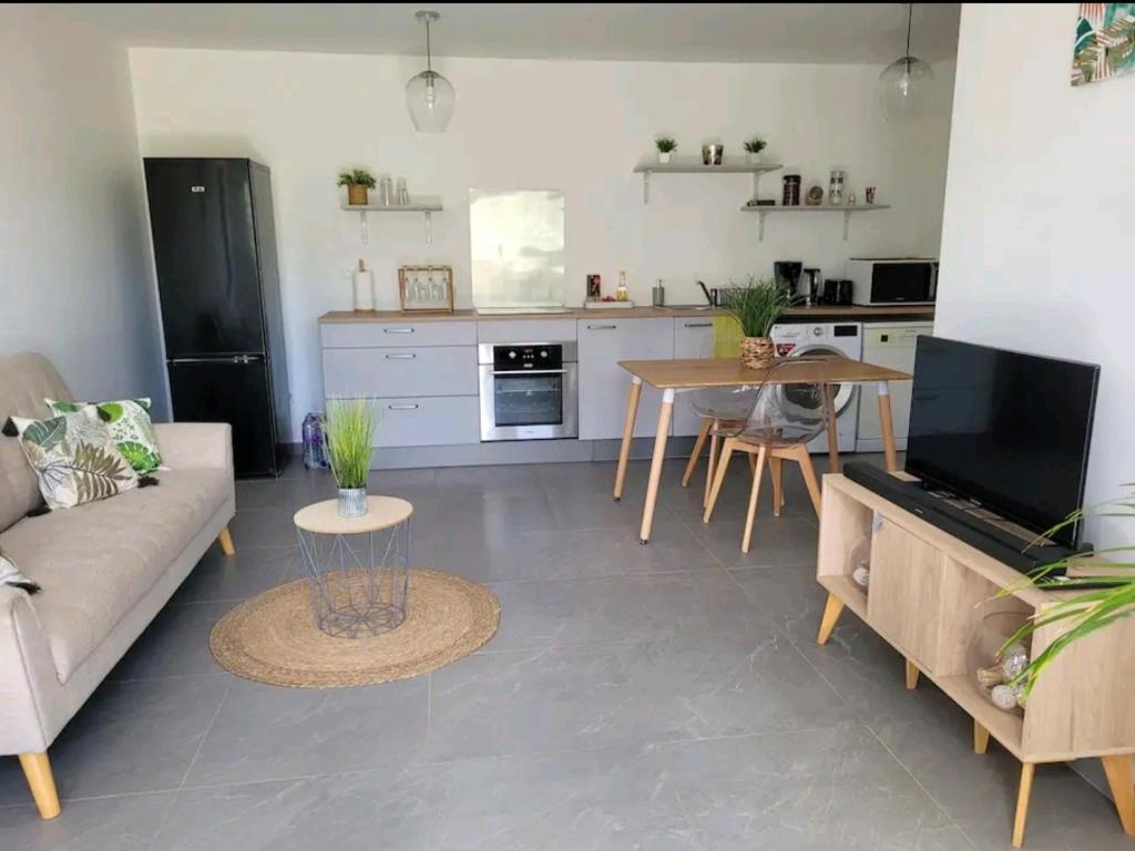 cocina y sala de estar con sofá y mesa en Superbe appartement cosy neuf, en Saint Martin