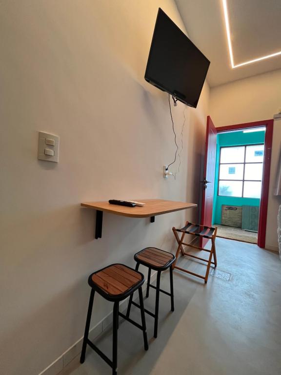a room with a table and two stools and a tv at Pousada Bat N Breakfast No Beco do Batman in São Paulo