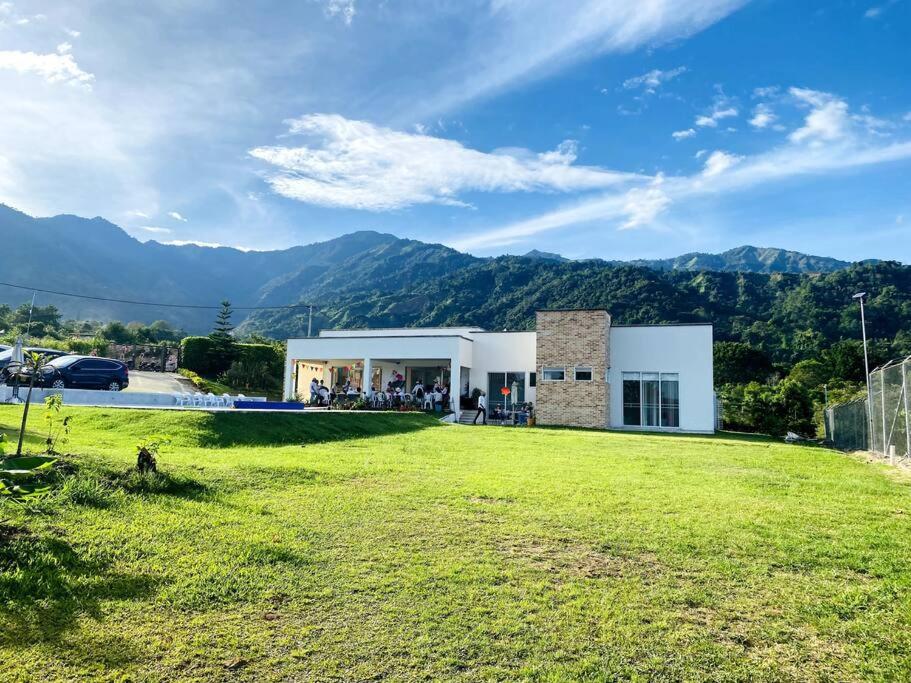 a building with a large grass field in front of it at Hermosa casa campestre! in Ibagué