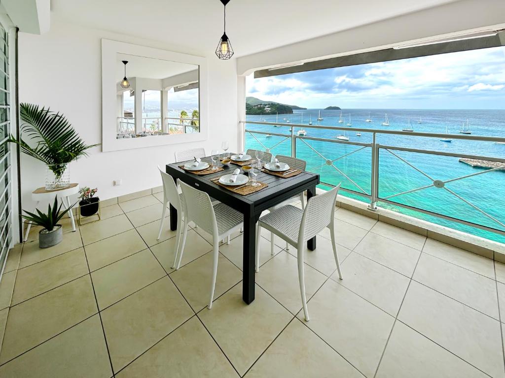 een eetkamer met een tafel en uitzicht op de oceaan bij Appartements T3 standing Vue mer époustouflante à quelques pas de la plage in Les Trois-Îlets