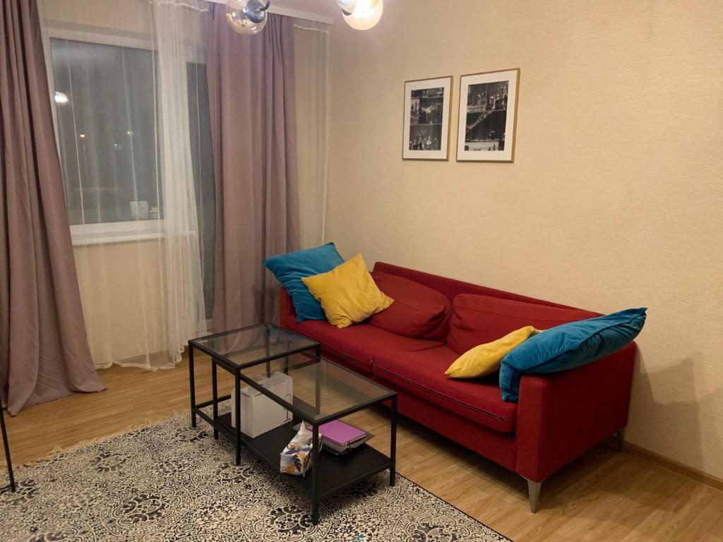 uma sala de estar com um sofá vermelho com almofadas azuis e amarelas em Cosy apartment near downtown and airport em Vilnius