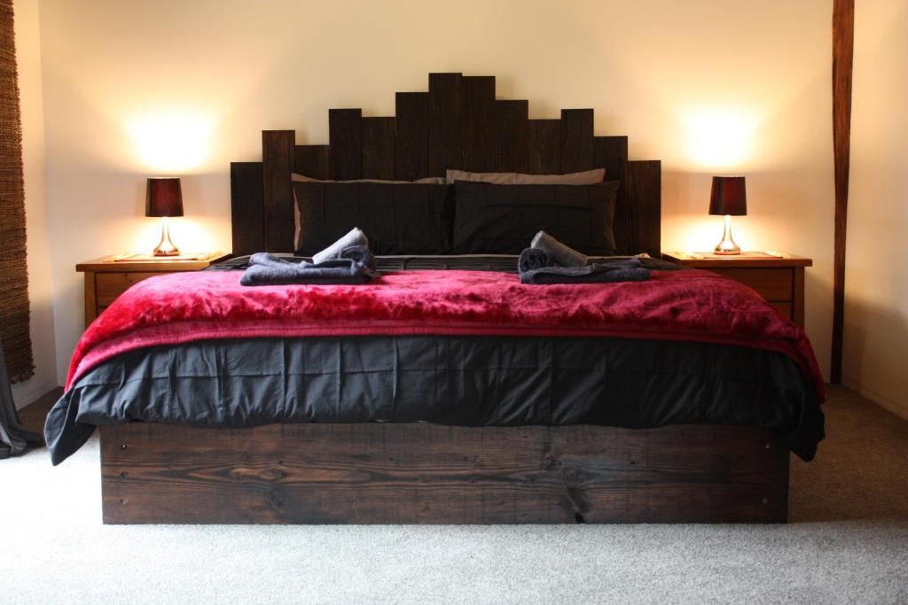 1 dormitorio con 1 cama grande con manta roja en La Boheme Secluded Luxury Spa Villa, en Daylesford