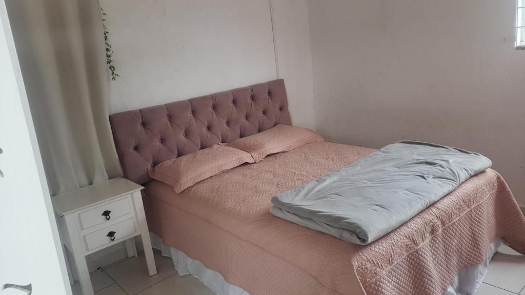 małe łóżko z różowym zagłówkiem i stolikiem nocnym w obiekcie Linda Casa Inteira c/ Acesso a Praia do Campeche w mieście Florianópolis
