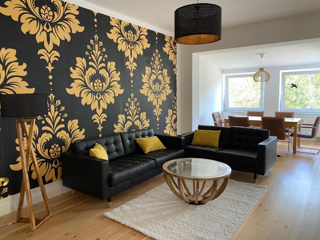 sala de estar con sofá negro y papel pintado de color amarillo en NEU ausgestattete Wohnung in Berlin - ruhige Lage, en Berlín