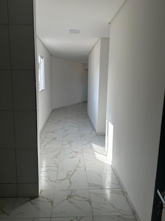 un pasillo vacío con paredes blancas y suelo de baldosa blanca en Casa união en Olinda