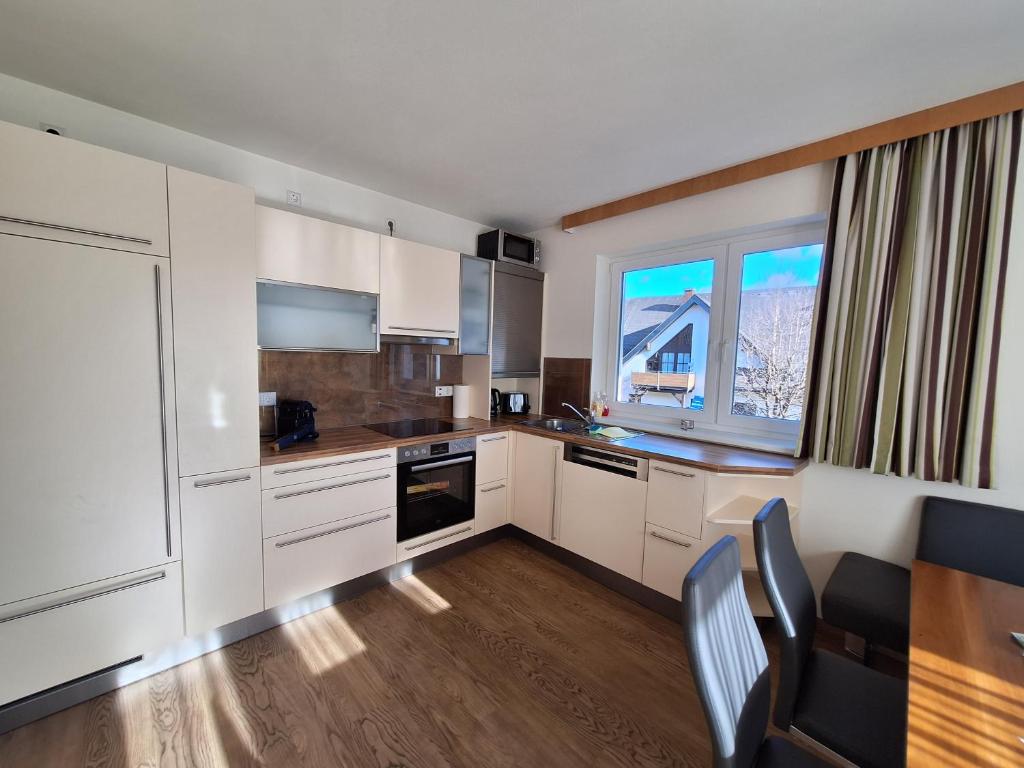 a kitchen with white cabinets and a table and a window at Die Schladmingerin in Schladming