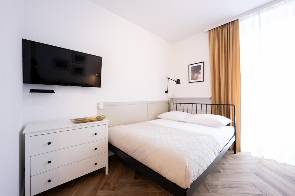 a bedroom with a bed and a tv on a wall at Native Apartments Pułaskiego 6 in Kraków