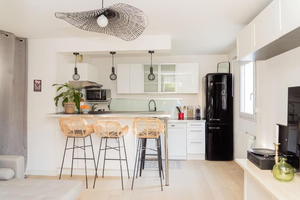 - une cuisine avec deux tabourets de bar et un réfrigérateur noir dans l'établissement Appartement Terrasse et Parking, à Aix-en-Provence