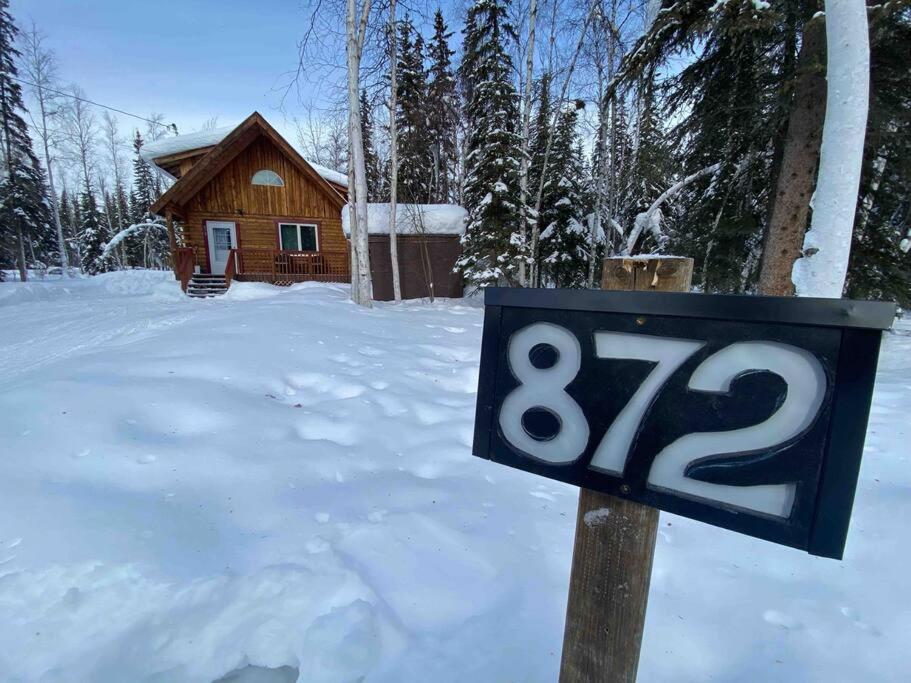 een bord in de sneeuw voor een blokhut bij Cozy Alaskan Log Home - Aurora overhead in Fairbanks