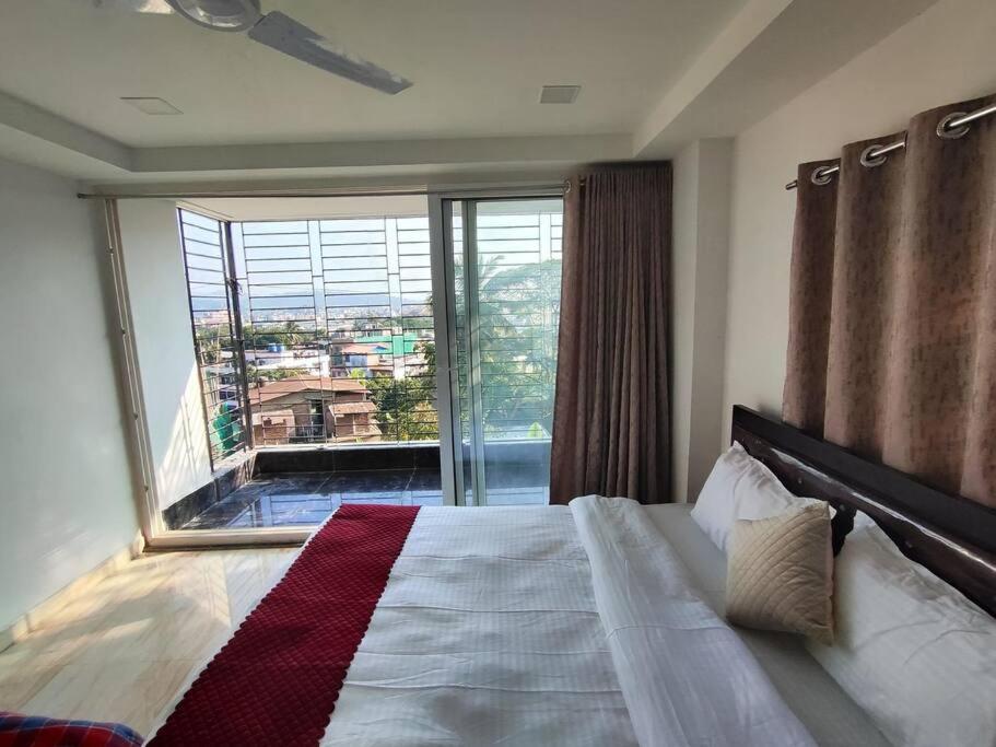 a bedroom with a bed and a large window at Lily Homes in Guwahati