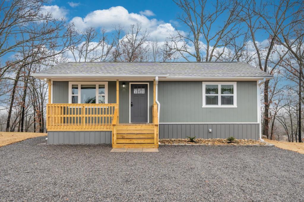 a small gray house with a porch and a door at Nordins Hillside Meadow View Cabin in Coffeyville