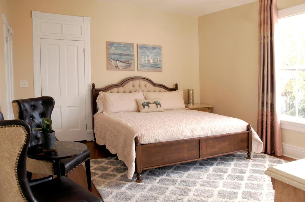 a bedroom with a bed and a chair and a window at MayLi Place Luxury King Suite Downtown St Augustine in Saint Augustine