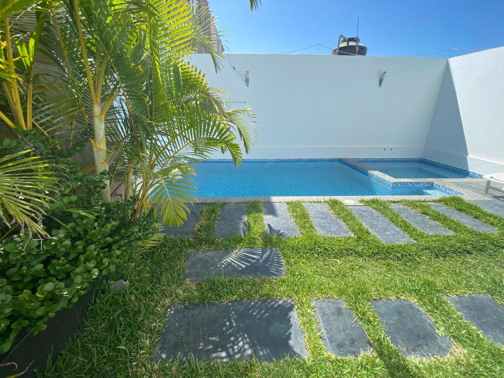 un patio trasero con piscina y césped en Killamoon House Paracas en Paracas