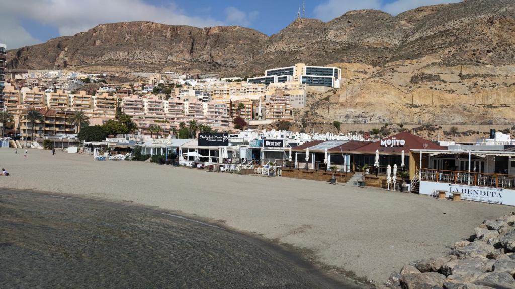 a group of buildings on a beach with a mountain at Ático con terraza en el puerto de Aguadulce in Aguadulce