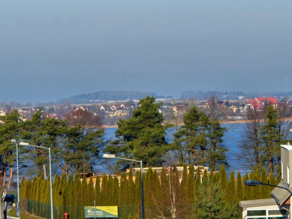 vistas a un río con árboles y una valla en Apartament blisko jeziora, en Ełk