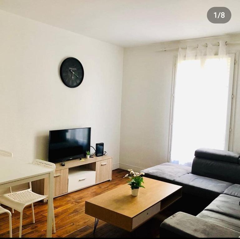 een woonkamer met een bank en een tv bij Appartement charonne in Parijs