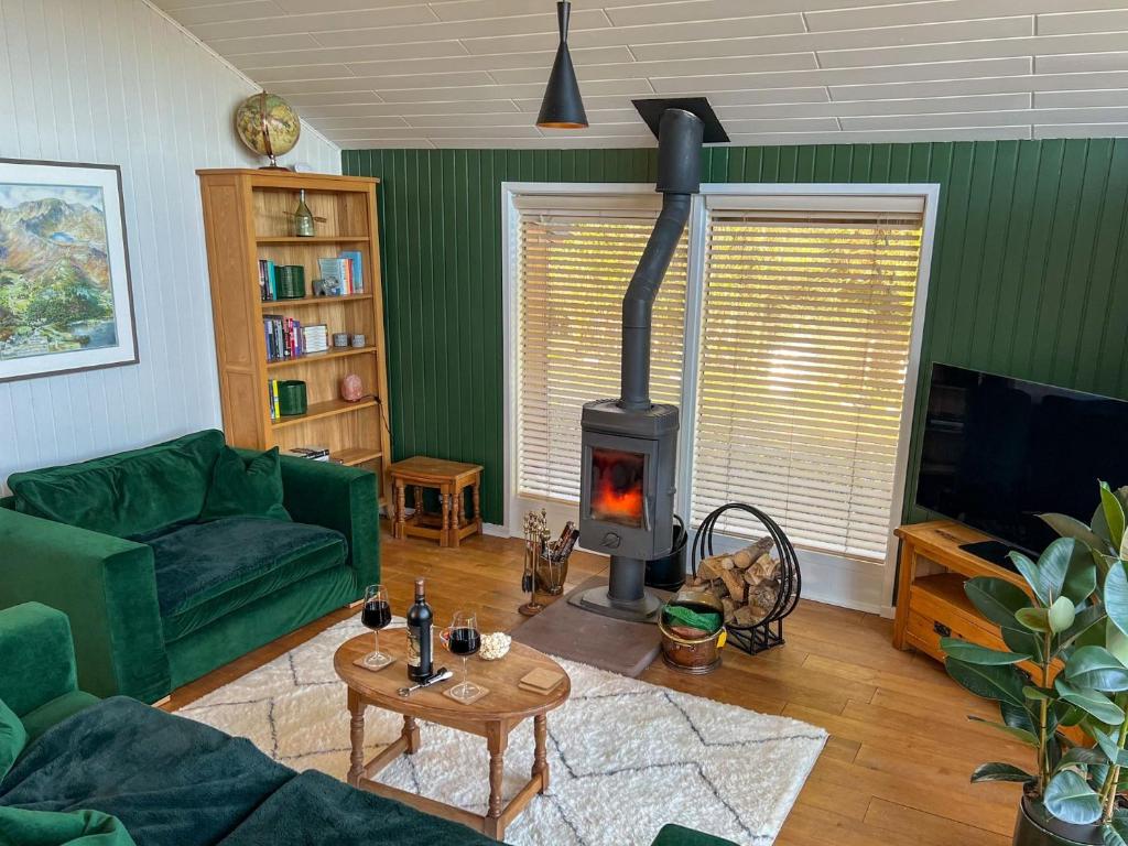 a living room with a fireplace and a green couch at Green Vale Lodge, Yanwath, Ullswater in Tirril
