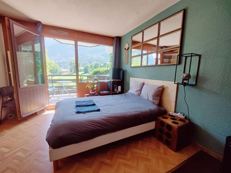 een slaapkamer met een groot bed en een groot raam bij Appartement ski in out 5 in Les Houches
