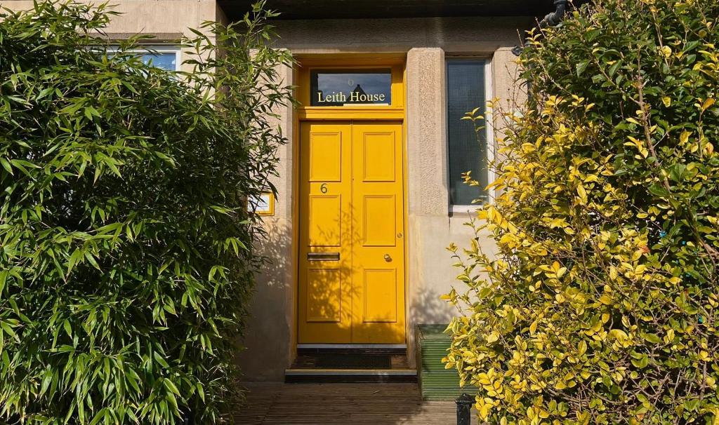 una puerta delantera amarilla de un edificio con arbustos en Leith House, en Edimburgo